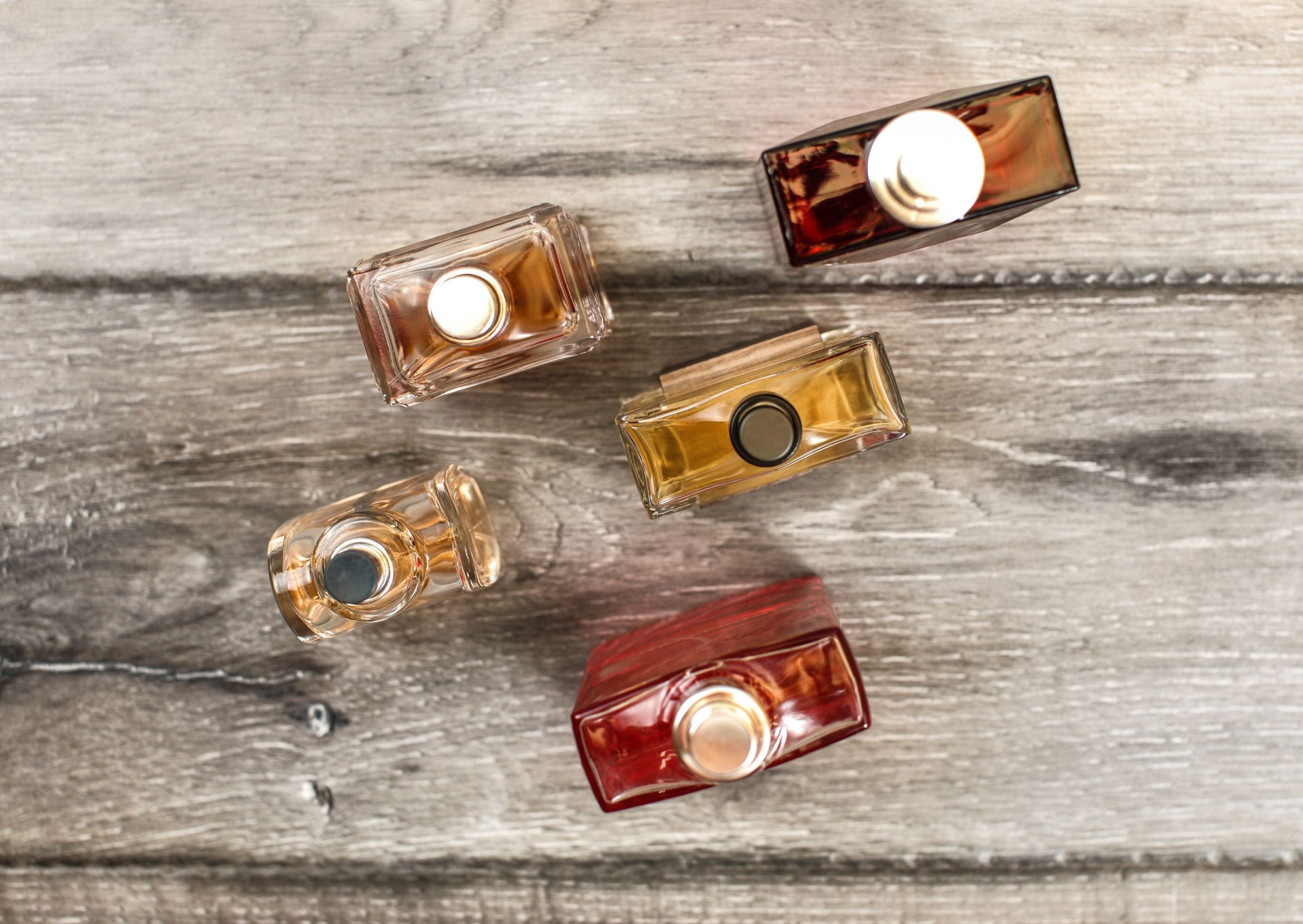 Tabletop view, men fragrances colourful  bottles, on wooden boards desk.